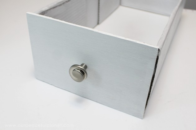 Learn how to make an inexpensive pull out cabinet organizer using a cardboard box so you can easily access things in the far reaches of your lower cabinets.