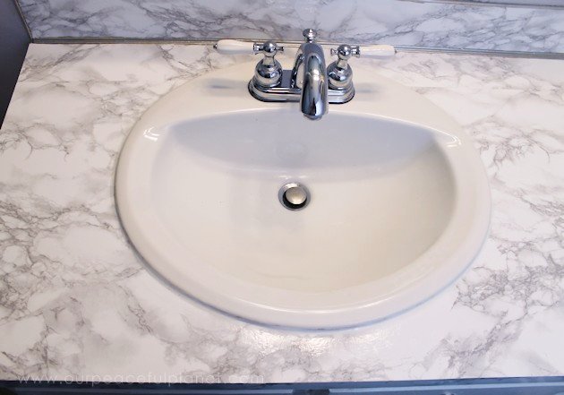 Transform your bathroom for only a few dollars with a contact paper countertop. You'll be amazed at how beautiful it looks & so will your family & guests!