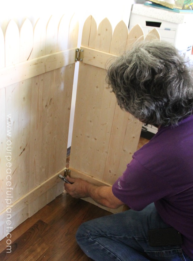 Add some whimsy to your home with this easy DIY picket fence fireplace cover. Made with wood slats and some hinges you can decorate it for any season. 
